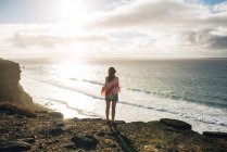 España, Fuerteventura, El Cotillo, vista trasera de la mujer mirando al mar al atardecer - foto de stock