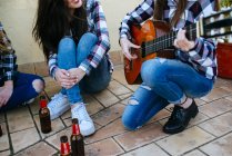 Женщина играет на гитаре, пока друзья слушают — стоковое фото