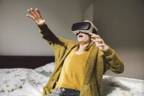 Awed donna indossando occhiali di realtà virtuale utilizzando le mani — Foto stock