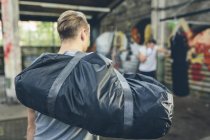 Athlete arriving on training ground with boxer exercising at punch bag on background — Stock Photo