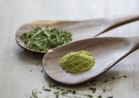 Moringa oleifera, powder and chopped leaves on wooden spoons — Stock Photo