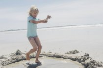 Blond boy playing with sand on the beach — Stock Photo
