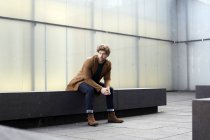 Germany, Cologne, stylish young man waiting on a stone bench — Stock Photo
