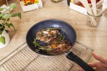 Steak with rosemary in pan over wire rack on table — Stock Photo