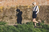 Donna camminando lungo muro di mattoni — Foto stock