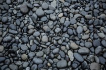 Pebble stones at beach as background — Stock Photo
