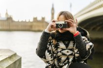 UK, London, young woman taking a picture near Westminster Bridge — Stock Photo