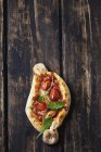 Kleine Pizza mit Rucola und Kirschtomaten auf dunklem Holz — Stockfoto