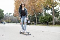 Young woman longboarding on the road — Stock Photo