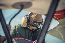 Ragazzo seduto in biplano indossando vecchio vestito da pilota — Foto stock