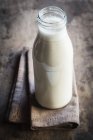 Vista close-up de leite de aveia caseiro em garrafa de vidro com toalha — Fotografia de Stock