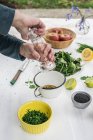 Cropped view of hands preparing salad seasoning with salt — Stock Photo