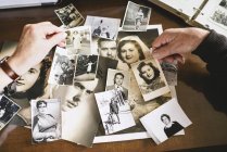 Руки пожилой пары с их старыми фотографиями — стоковое фото