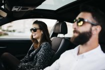 Jovem casal sorrindo dirigindo em um carro — Fotografia de Stock