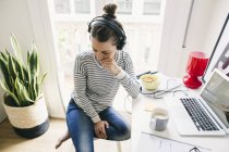 Mujer sentada en la mesa con auriculares - foto de stock