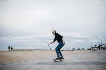 Skateboarder escuchando música con auriculares - foto de stock
