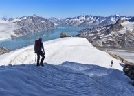 Гренландия, Кулусук, альпинисты прогуливаются по Швейцарским Альпам возле озера — стоковое фото