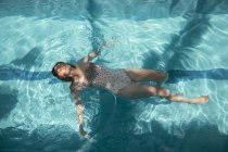 Woman floating on water of a swimming pool — Stock Photo