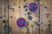 Two glasses of chia blueberry pudding and two tea spoons on wood — Stock Photo