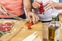 Casal de corte de tomates em tábua de cortar — Fotografia de Stock
