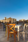 Sicilia, Marzamemi, tavoli e sedie di ristorazione, cappella sullo sfondo — Foto stock