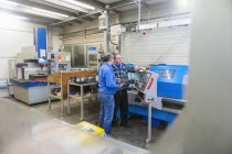 Due uomini in fabbrica che parlano alla macchina per la produzione di stampi — Foto stock