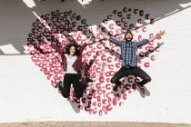 Couple jumping in front of painted heart — Stock Photo