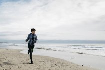 Frau läuft im Winter am Strand — Stockfoto