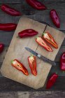 Chopped red pointed pepper on chopping board, halved, pocket knife — Stock Photo