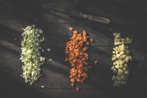 Рядами нарізані моркву, картопля і цибуля з ножем на темного дерева — стокове фото