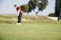 Golfista desfocado jogando golfe no verde de um campo de golfe — Fotografia de Stock