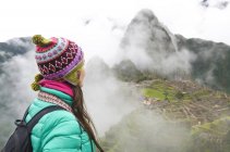 Peru, Frau genießt Machu Picchu vor Sonnenaufgang mit den Ruinen, die von Nebel umgeben sind — Stockfoto