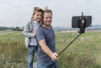 Портрет батька і Маленький син, зроблену фотографію з палицею selfie в природі — стокове фото