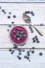 Glass of chia blueberry pudding and tea spoon on wood — Stock Photo