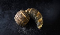 Rouleau de graines de pavot et croissant de graines de pavot sur fond sombre — Photo de stock