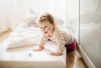 Ritratto di bambina sorridente che striscia sul materasso — Foto stock