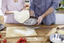 Casal preparando massa de pizza na cozinha — Fotografia de Stock