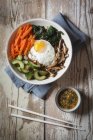Tazón de arroz coreano vegetariano con setas, espinacas, pepino, zanahoria y huevo frito - foto de stock