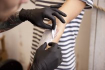 Hände des Tätowierers entfernen Schablone aus dem Unterarm eines Kunden — Stockfoto