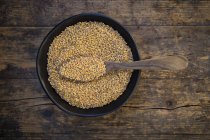 Bowl of organic einkorn wheat on dark wood — Stock Photo