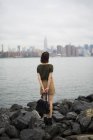 USA, New York City, back view of young woman looking to Manhattan skyline from Williamsburg bank — Stock Photo