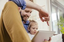 Padre mostrando alla sua figlioletta qualcosa sul tablet digitale — Foto stock