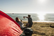 Junges Paar zeltet am Meer und trinkt Bier bei Sonnenuntergang — Stockfoto