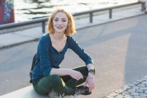 Молодая привлекательная блондинка с умными часами, сидящая на улице — стоковое фото