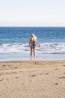 Spain, Tenerife, young female surfer standing on sandy beach — Stock Photo