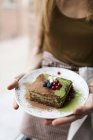 Mãos femininas segurando bolo matcha na placa — Fotografia de Stock