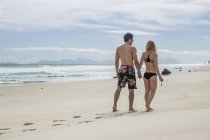 Young couple walking hand in hand on the beach — Stock Photo