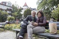Літня пара з книгою, сидячи на лавці в місті — стокове фото