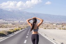Young female athlete walking on country road — Stock Photo