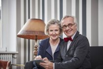 Sorridente coppia anziana seduta sul divano con tablet — Foto stock